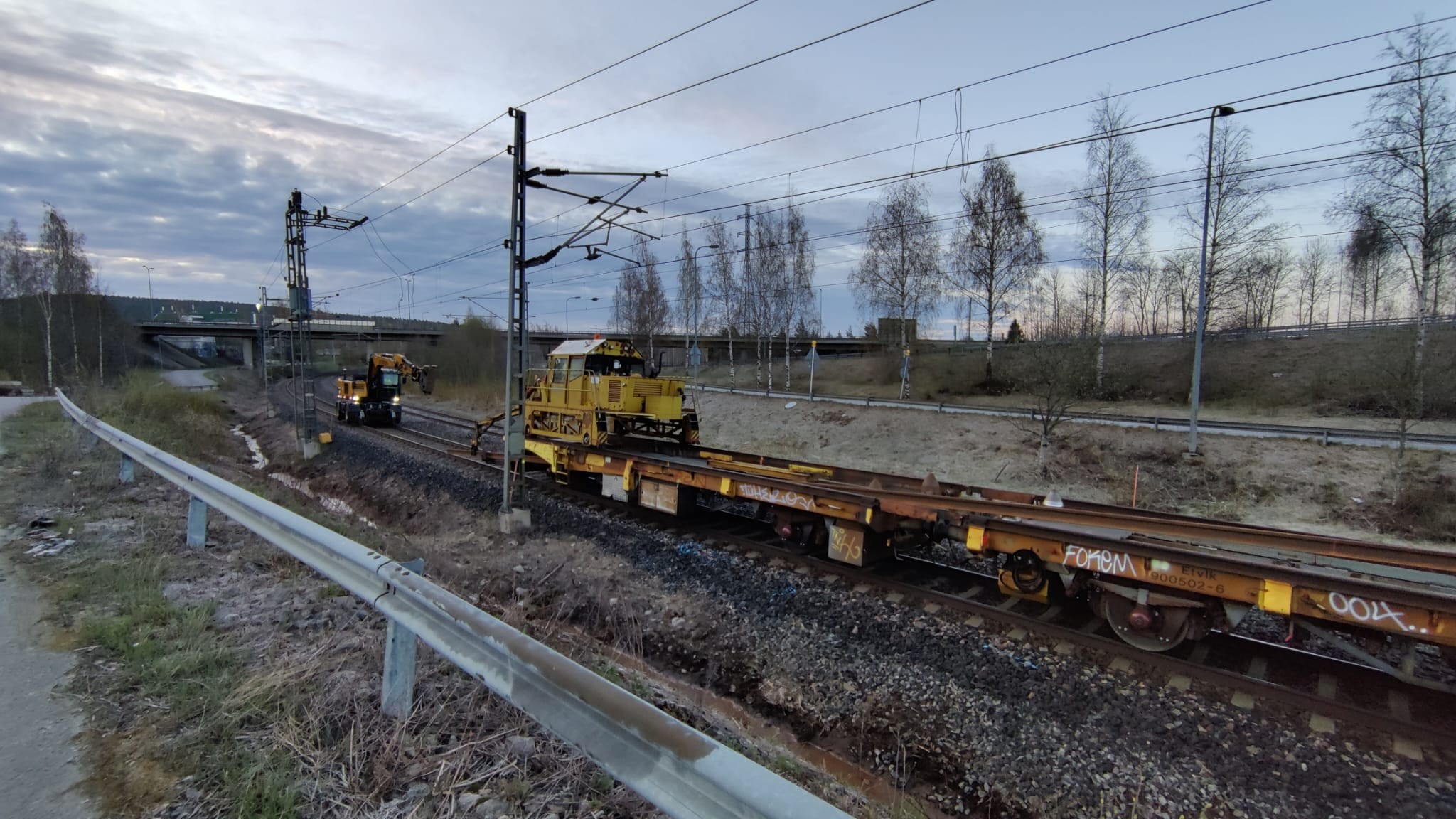 Viimeinen kiskopari syötetään vaunustosta. Kaivinkone ottaa kiskosta kiinni ja auttaa tasoittamaan kiskoon kohdistuvaa pystysuuntaista kallistusta, tämän jälkeen kaivinkone ankkuroi kiskon laskutapahtumaa varten.