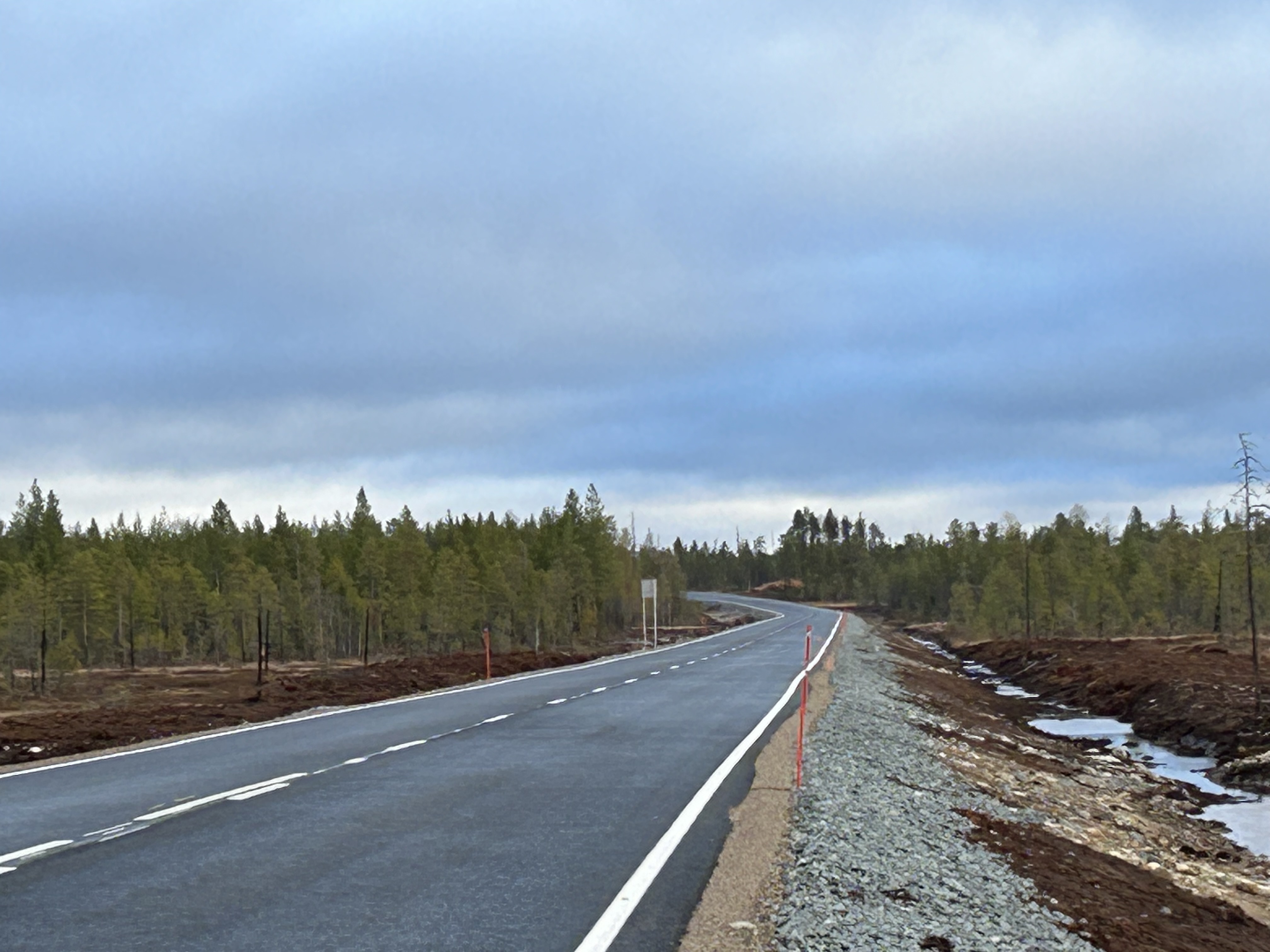 Suhangon kaivostie Ranualla. Etualalla näkyy uutta tietä ja sivuilla metsää sekä kuvan yläpuolella pilvistä taivasta. 