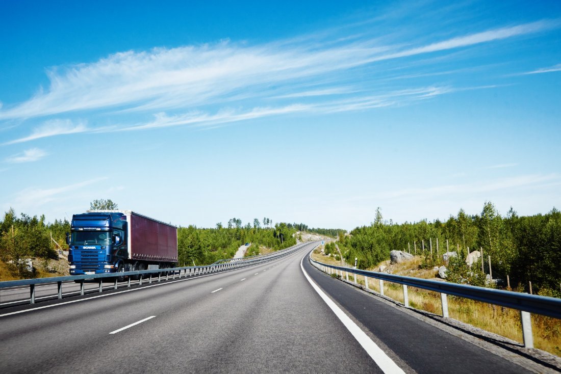 En motorväg på sommaren en solig dag. Tung trafik körs i andra körfältet