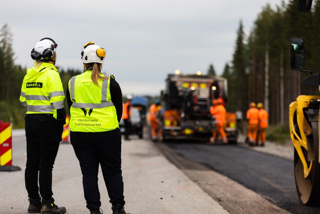 Kuvassa kaksi henkilöä katsomassa tien rakentamista.