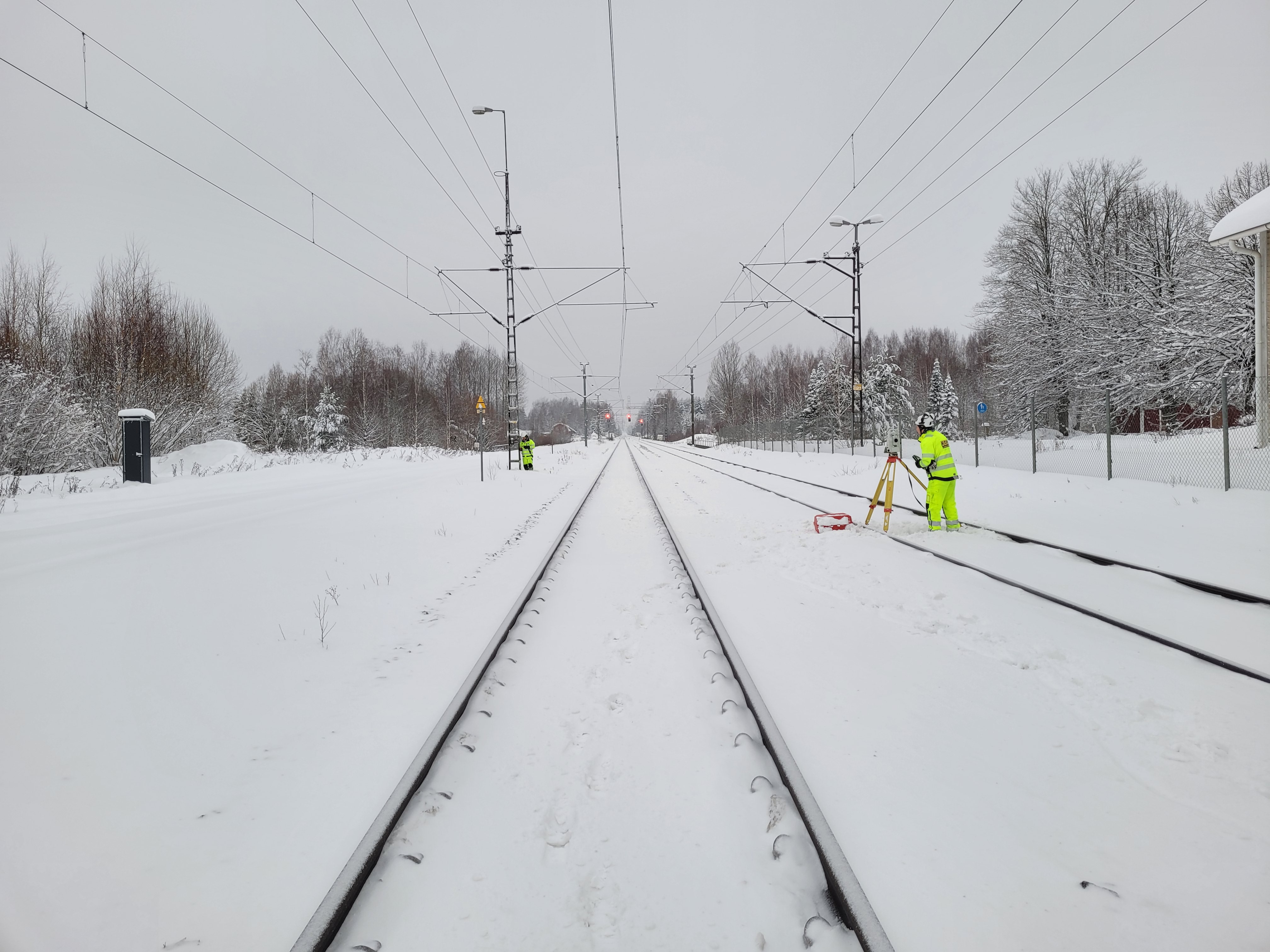 Henkilöitä työskentelemässä mittausten parissa talvella radalla