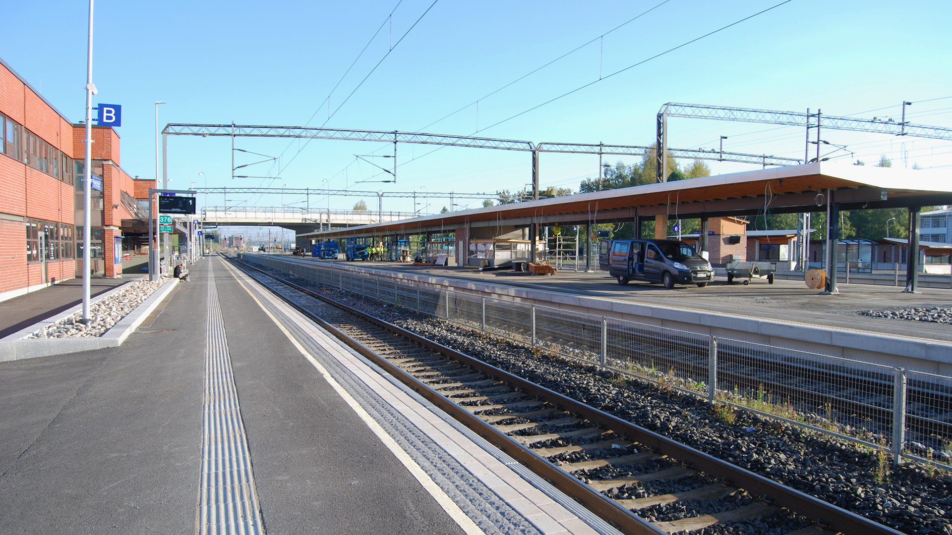 Rautatieaseman henkilöratapiha. Vasemmalla punatiilinen asemarakennus, oikealla raiteet ja asemalaiturit.