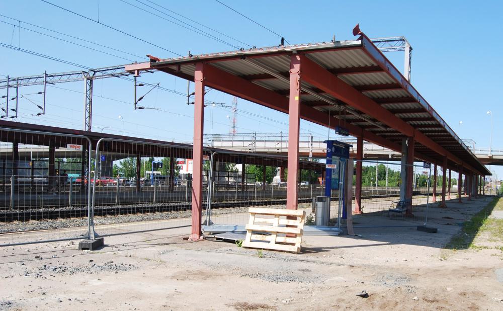 Rautatieaseman laiturikatos, jonka takana näkyy rata. Katoksen vieressä ja alla kulkee metallinen työmaa-aita.
