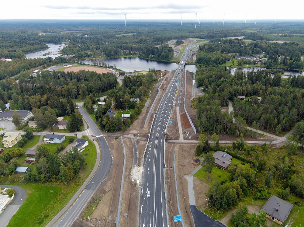 valtatie, maanteitä, autoja, risteyksiä, meluaitaa, alikulkuja, taloja, metsää, joki, tuulivoimaloita, siltoja