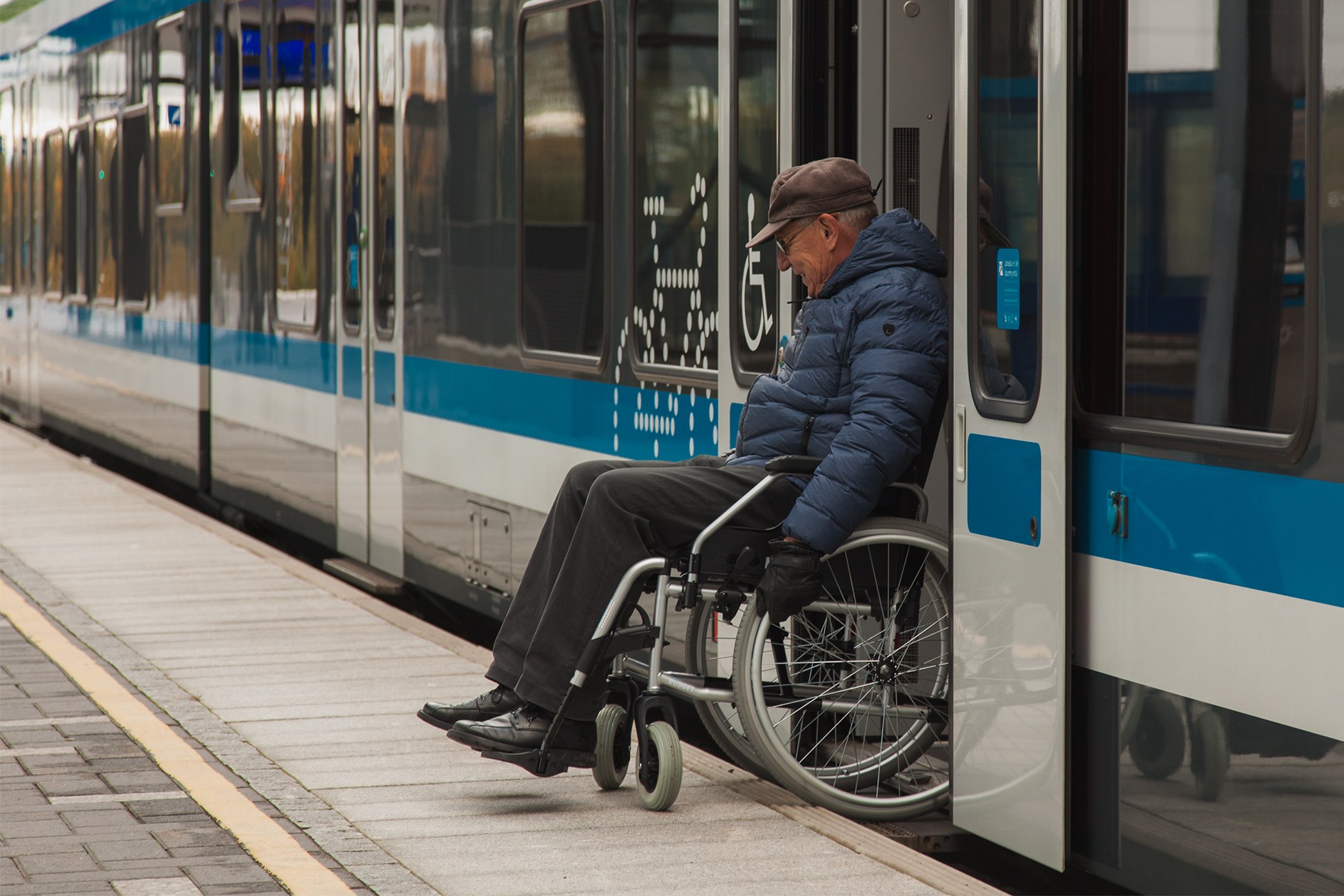 Mies pyörätuolissa peruuttaa laiturilta junaan