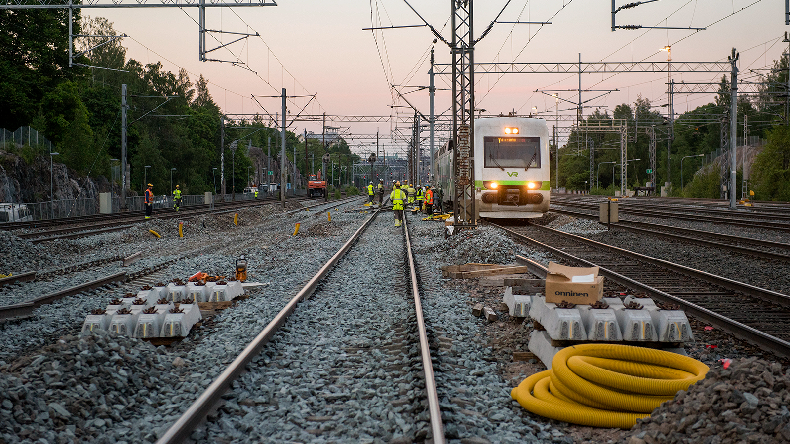 Ratatyöntekijöitä tekemässä vaihdetyötä junaradalla aamuyön auringon noustessa. SIJAINTI: Välillä Helsinki-Pasila.