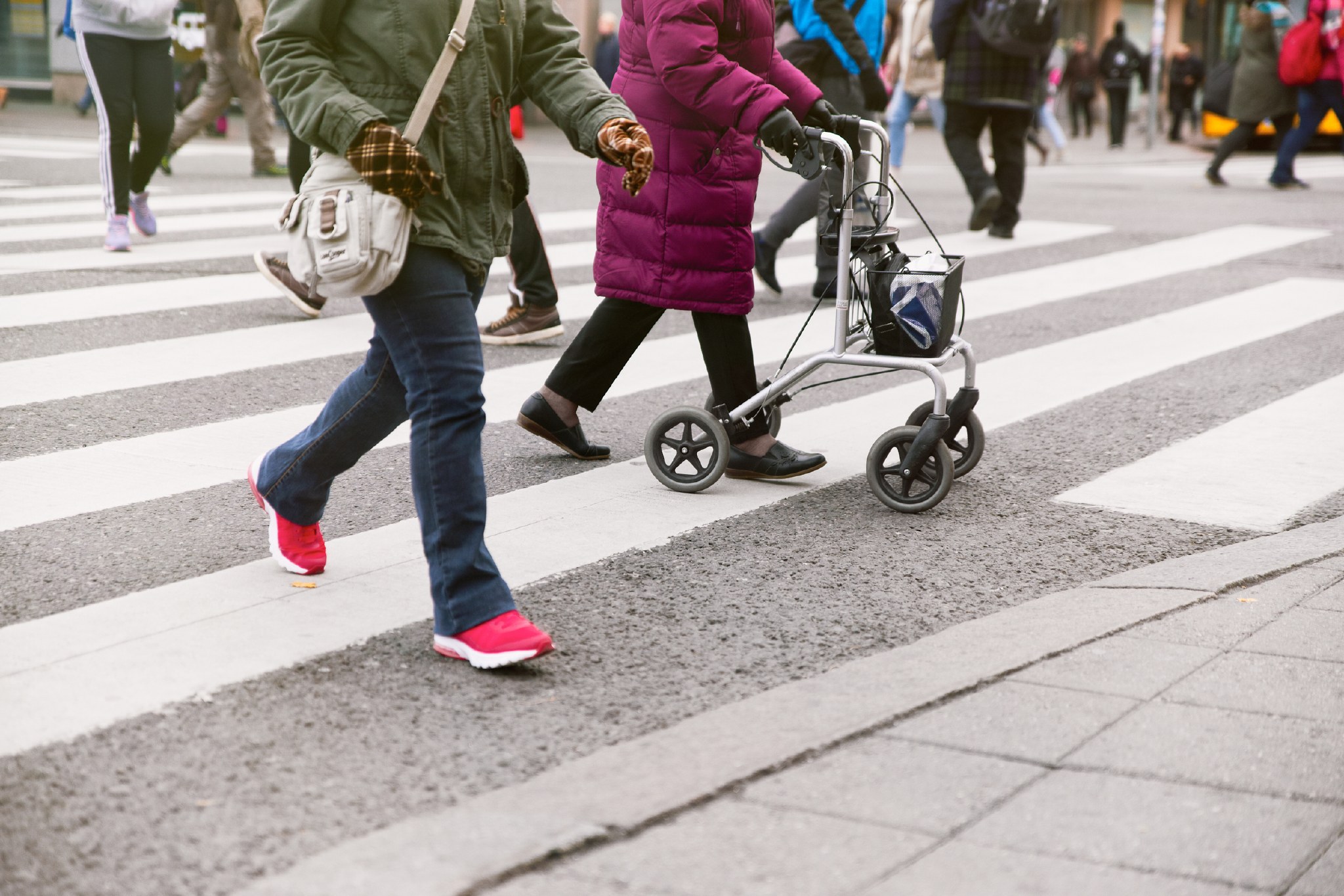 Jalankulkijoita suojatiellä. Yhdellä henkilöllä on rollaattori.