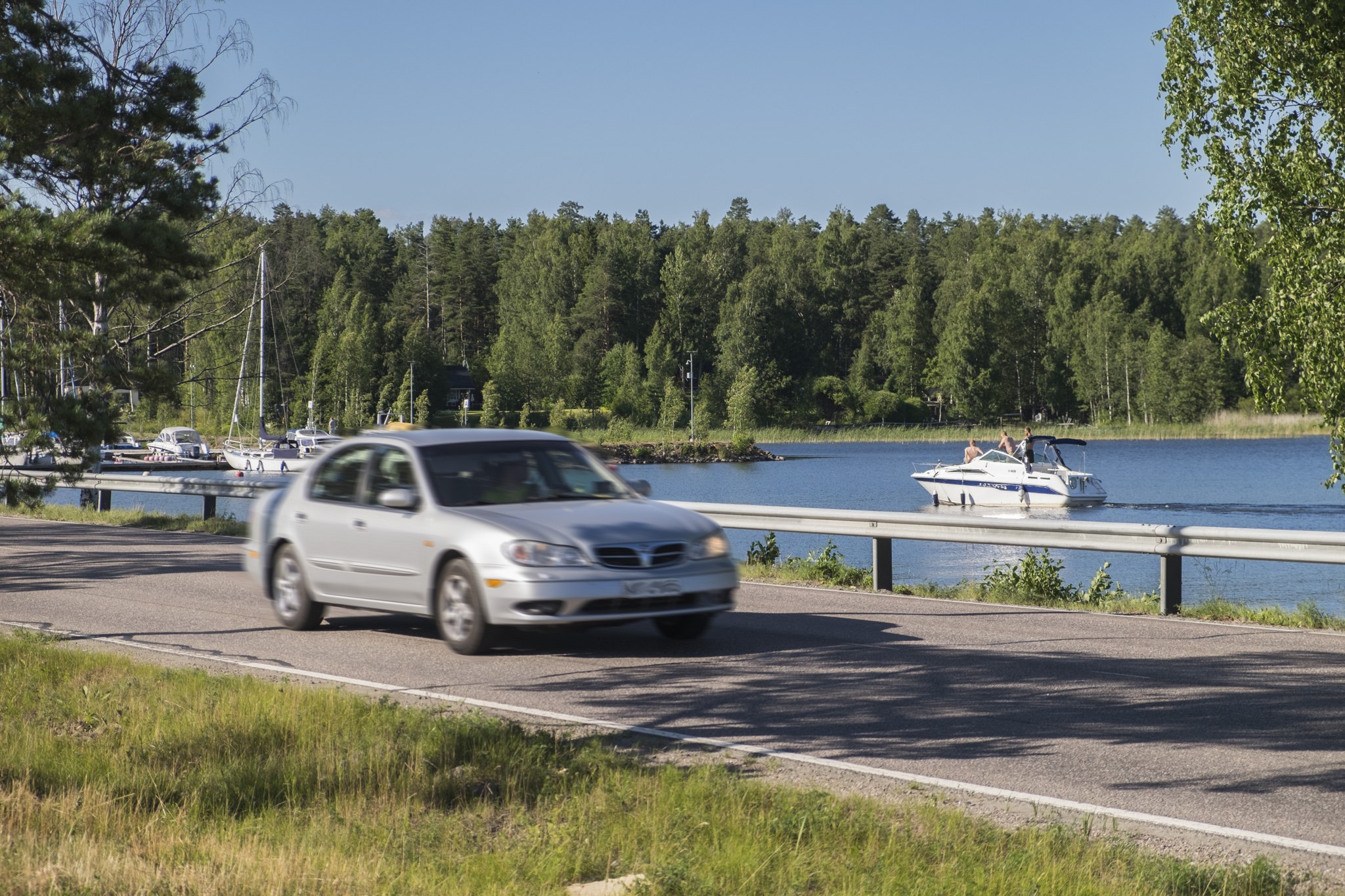 Auto ja vene kesäisessä maisemassa.