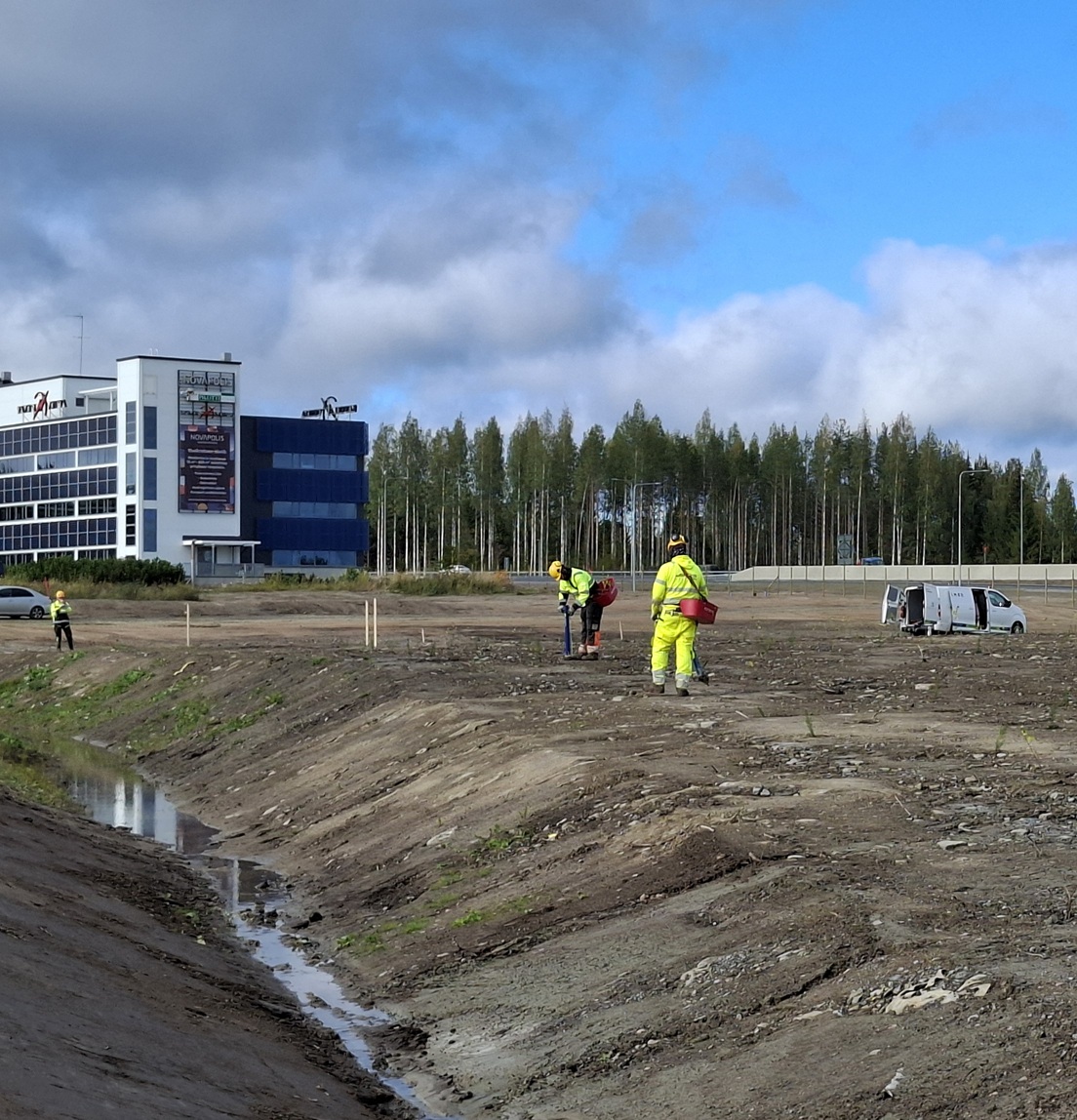 Työntekijöitä heijastavissa työvaatteissa työskentelee avoimella rakennustyömaalla.