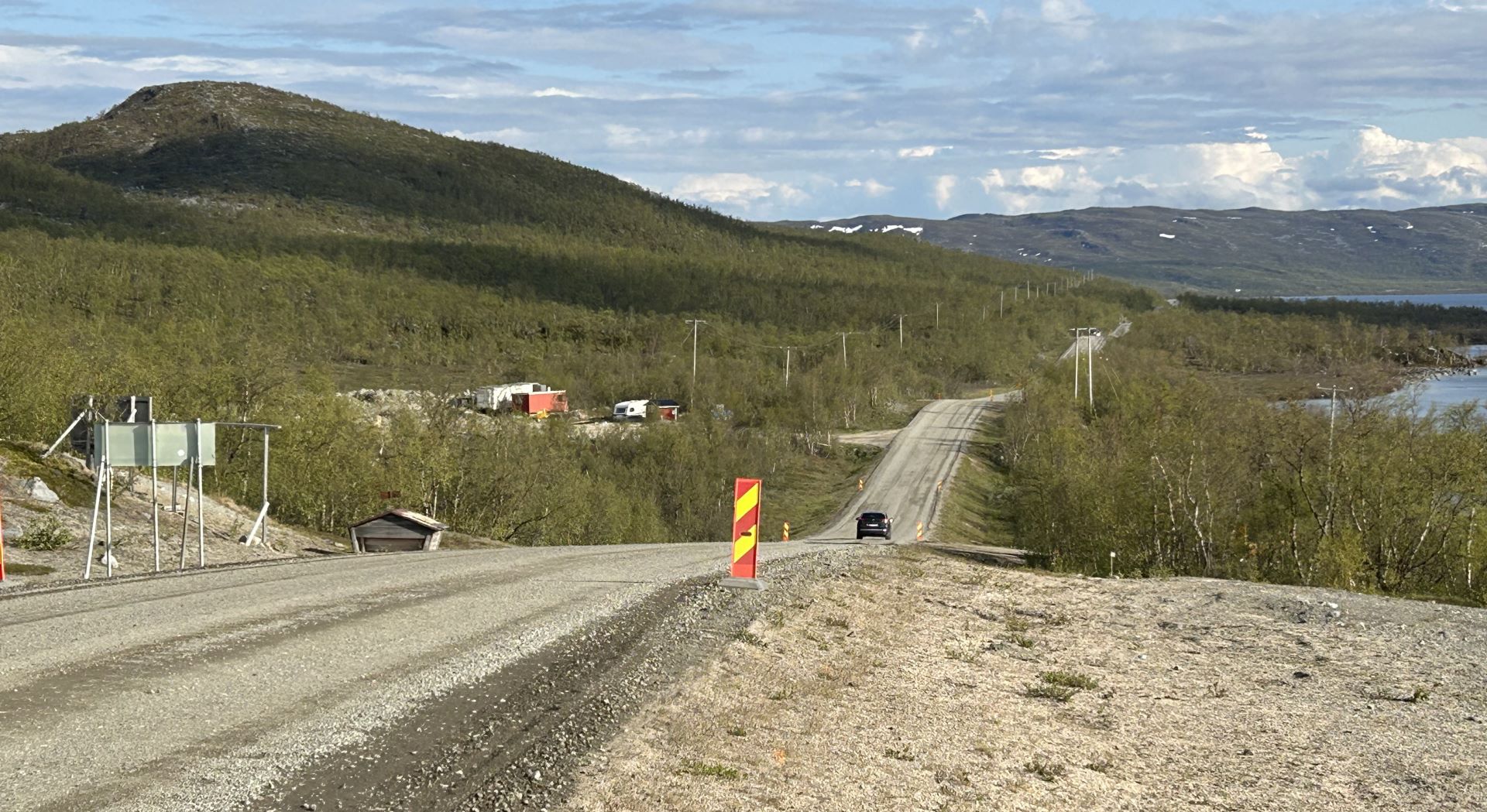 Kuva tietyömaasta Ailakkalahti-Kilpisjärvi-välillä Enontekiöllä kesäkuussa 2025. Tien pinta soralla työmaan kohdalla, taustalla tuntureita ja järvimaisema.