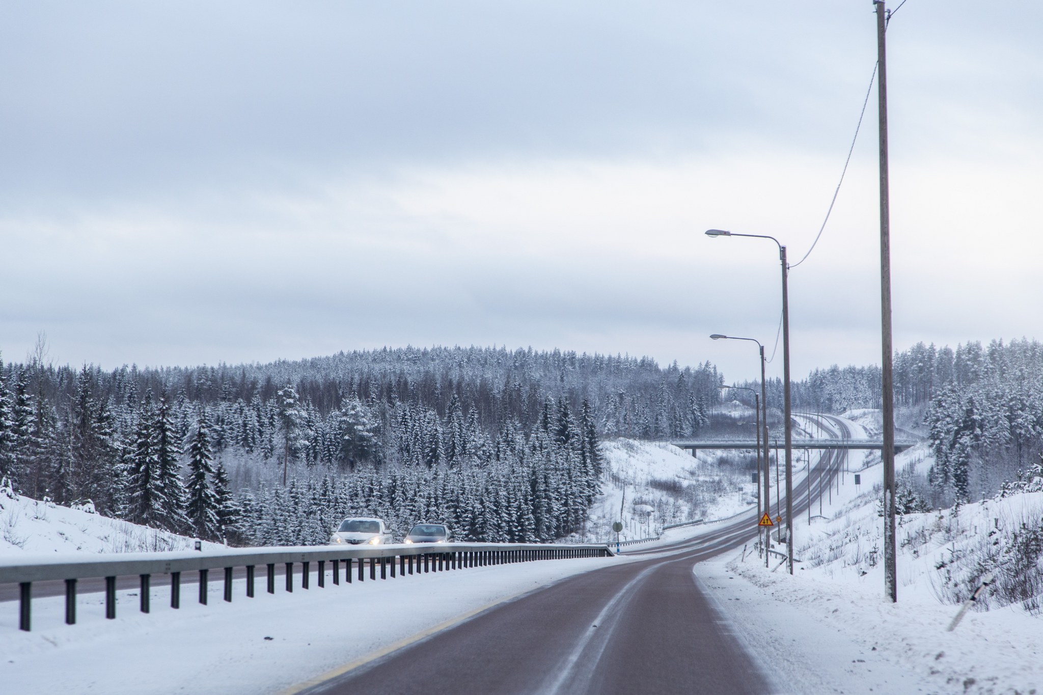 Kuvituskuva talvisesta maantiestä, jossa keskikaide parantamassa turvallisuutta.