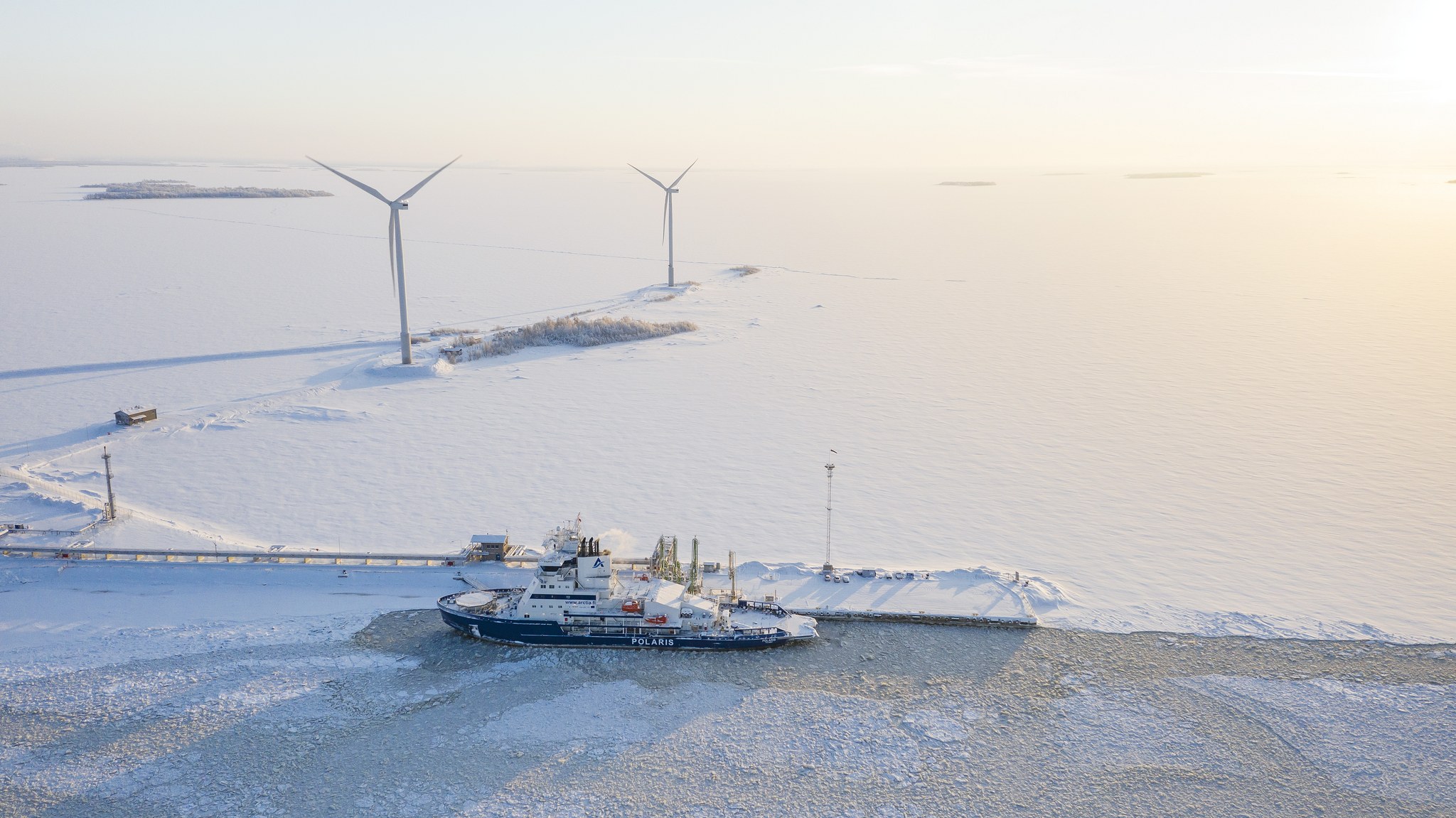 Ilmakuva jäänmurtajasta ja tuulivoimaloista talvella.
