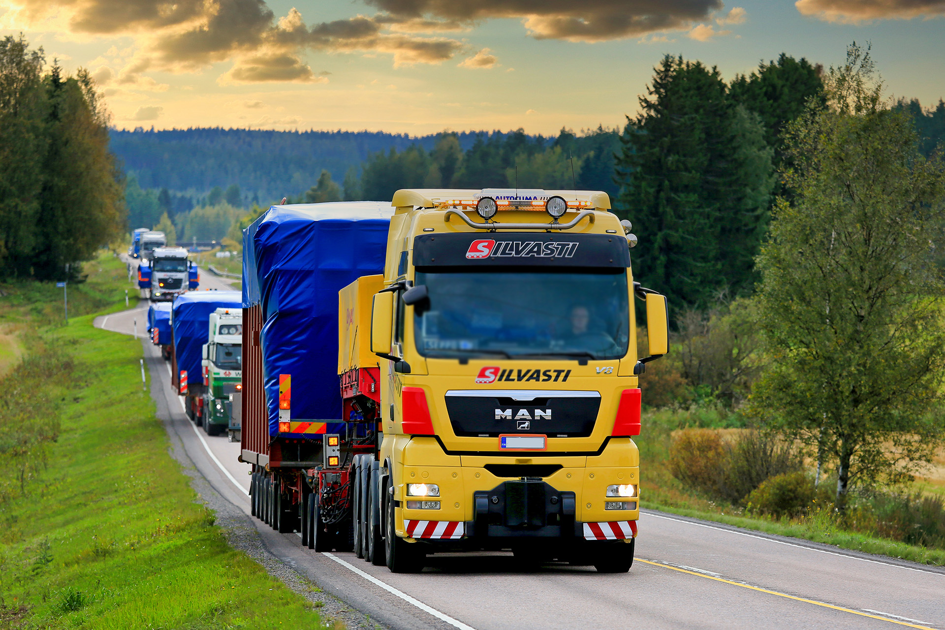 Erikoiskuljetus tiestöllä, monta isoa rekkaa peräkkäin.
