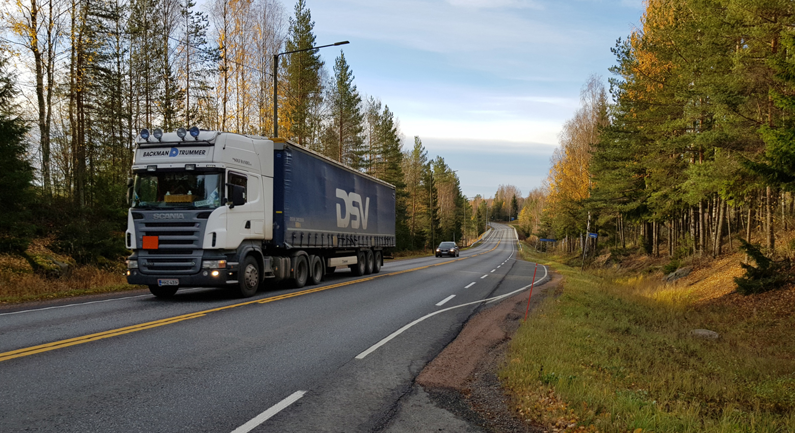 Syksyinen kuva tieosuudelta, jossa kulkee rekka. 