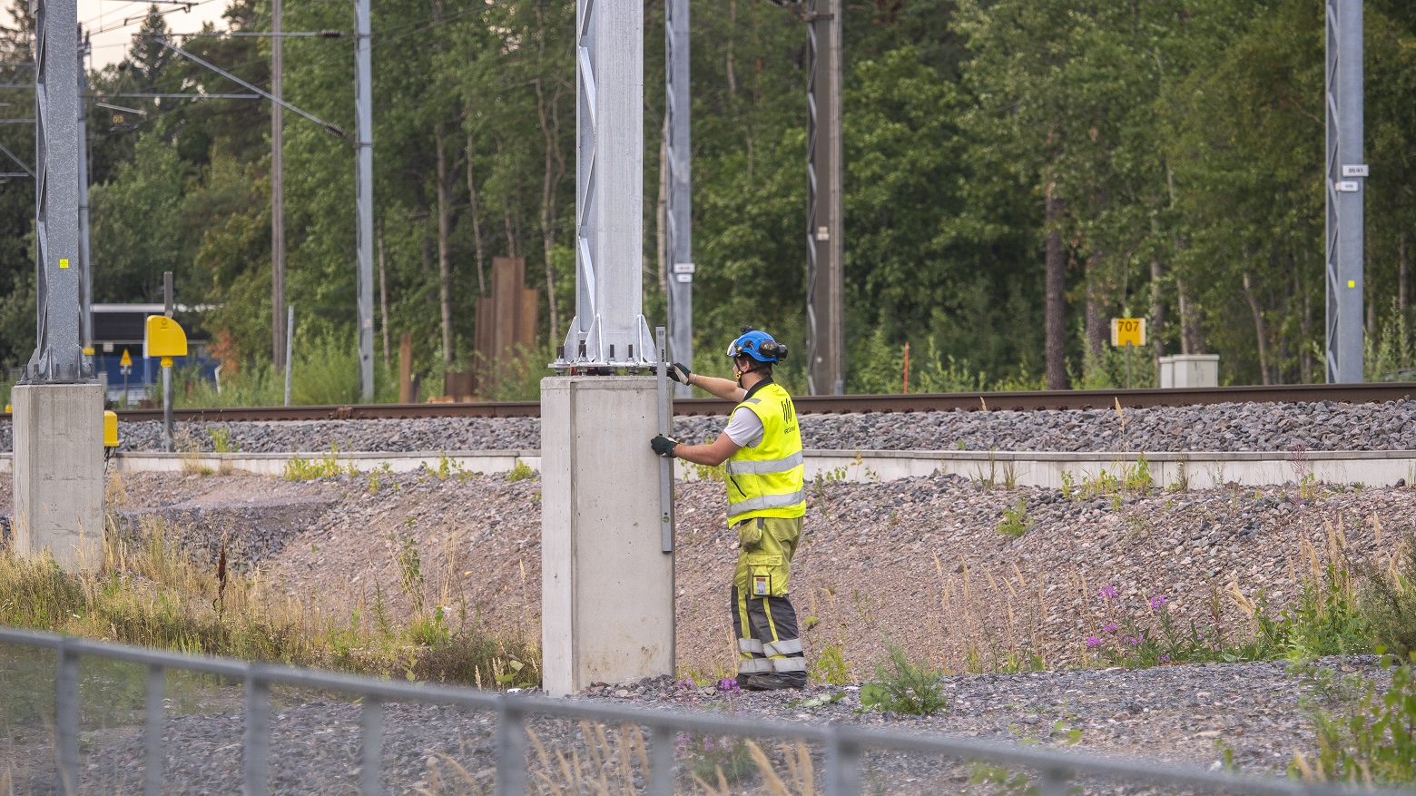 Junaraiteiden läheisyydessä ammattihenkilö tekee asennustöitä. Kuva: Jussi Pajunen.