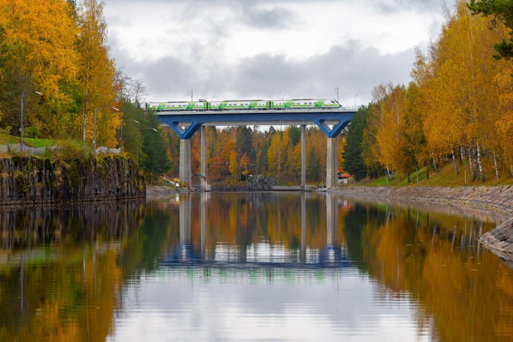 Silta näkyy veden yllä syksyisessä maisemassa. Puissa on keltaisia lehtiä.