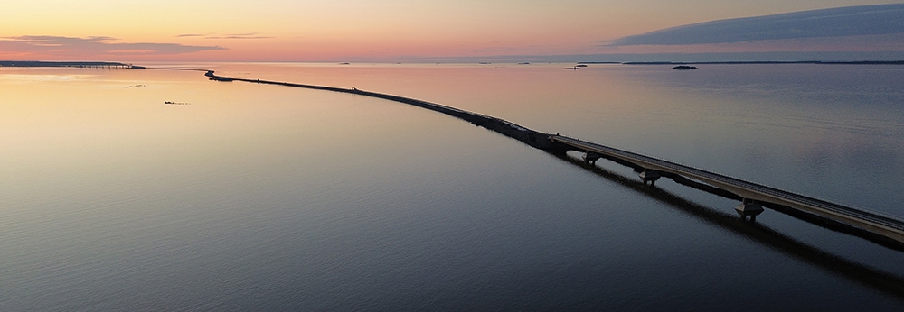 Kiinteä yhteys mutkittelee merimaisemassa siltoineen ja pengerteineen auringon laskiessa.