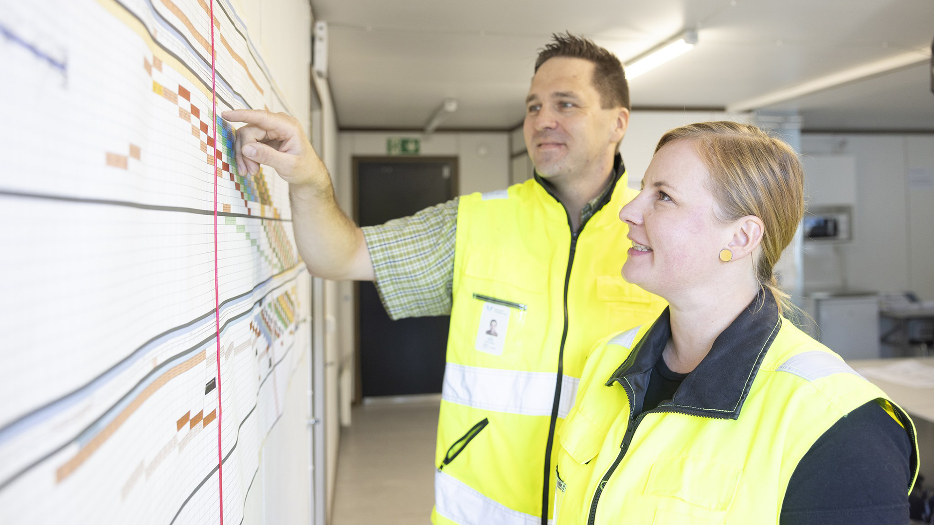 Projektipäälliköt tarkastelevat seinälle kiinnitettyä hankkeen tahtiaikataulua.