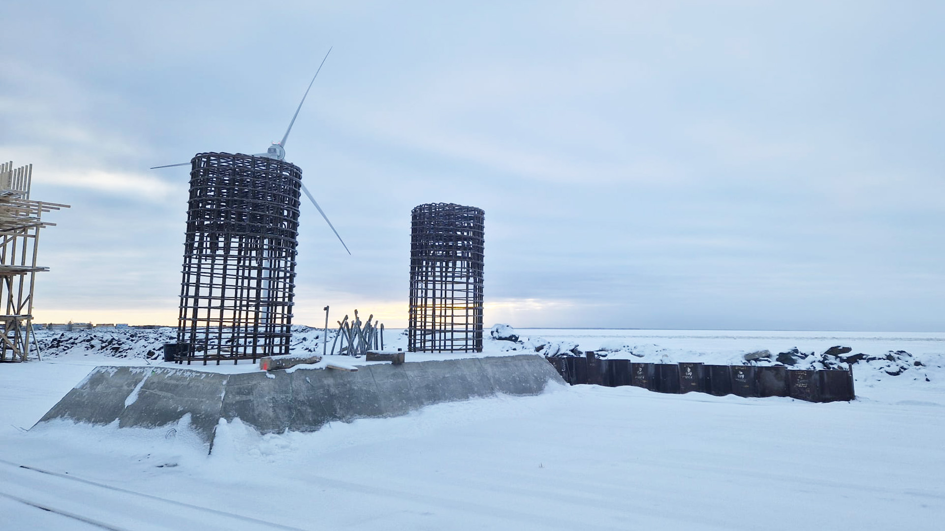 Betoninen jäänsärkijä ja siitä nousevat sillan tukipilarien raudoitukset lumipeitteisellä siltatyömaalla.