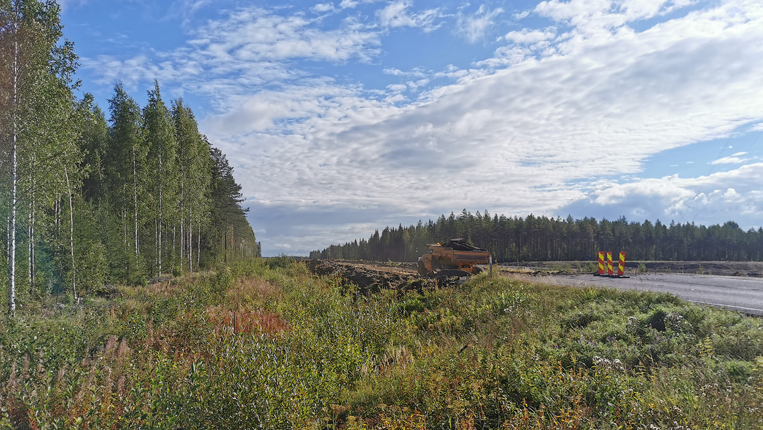 Näkymä tienpientareelta Vt 5 Mikkeli-Juva työmaale, taustalla kiviä ajava kuorma-auto.