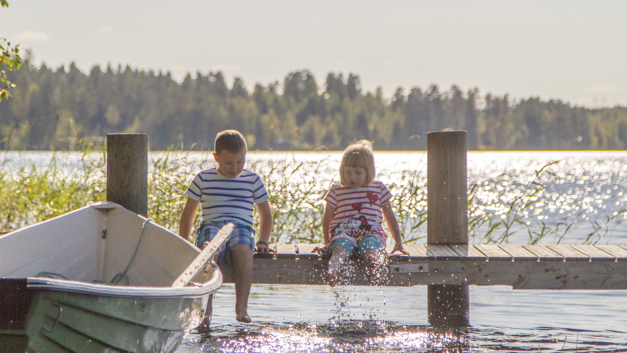 Kaksi lasta istuu laiturilla aurinkoisena kesäpäivänä. Kuva: Visit Mikkeli.