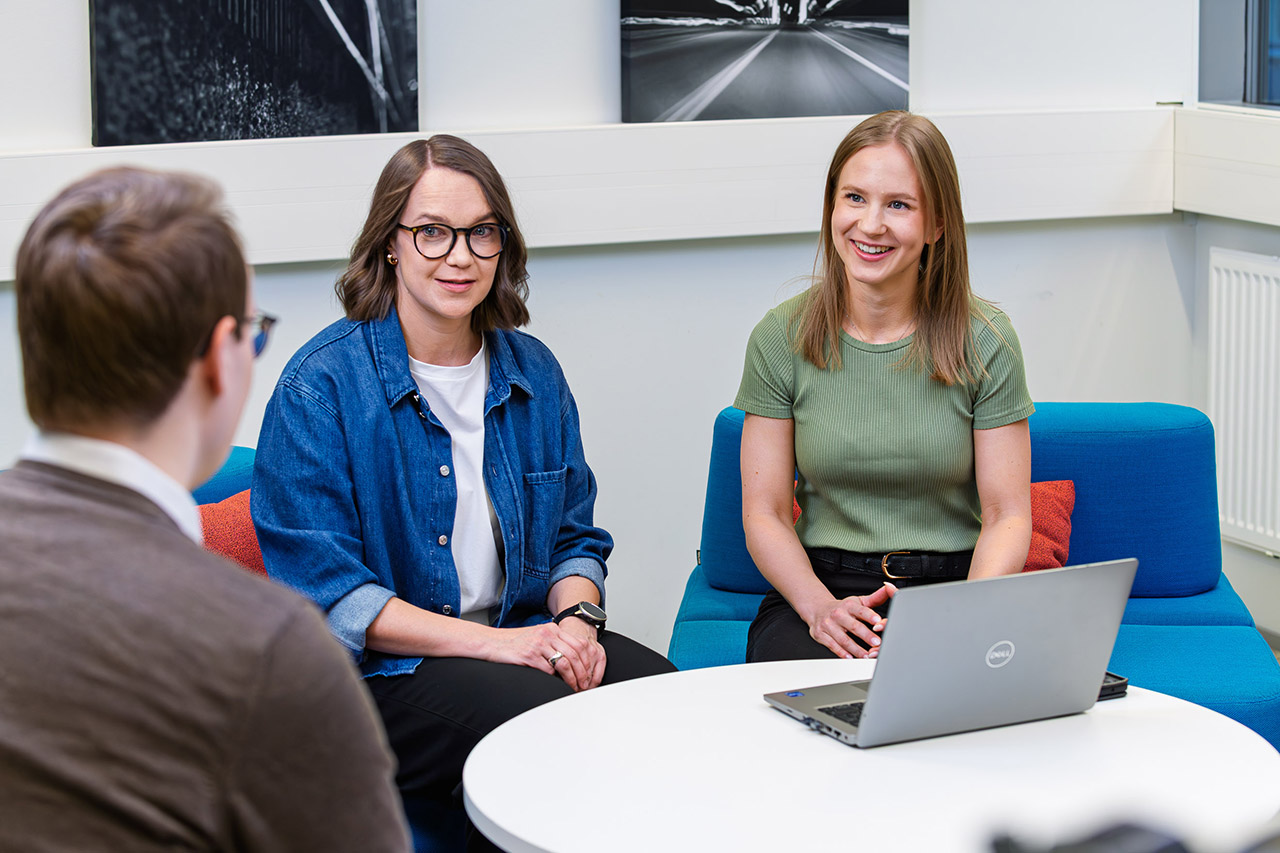 Kolme henkilöä keskustelee, kaksi heistä on kasvot kameraan päin.