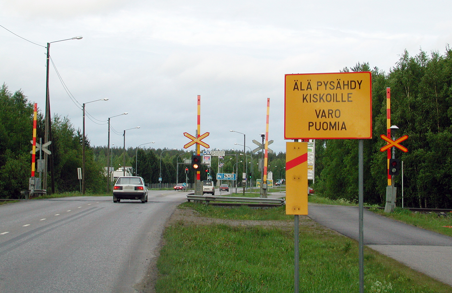Kuvassa tasoristeys, jossa ohjemerkkejä ja autoja ylittämässä sitä.