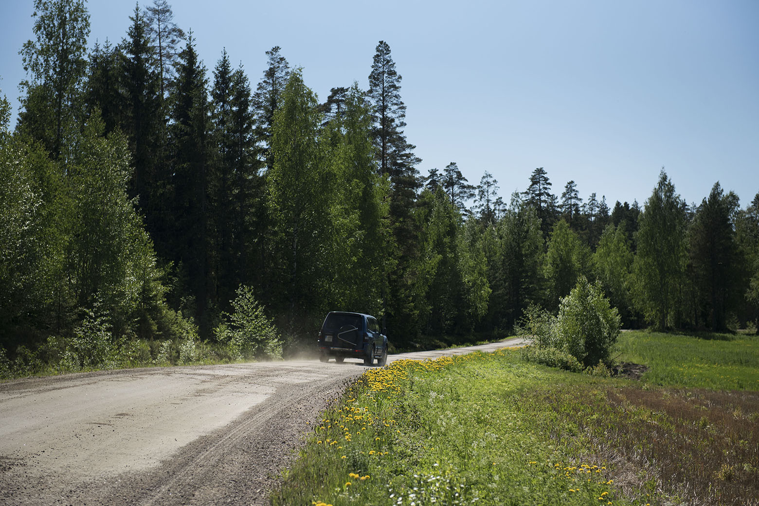 auto ajaa pölyävällä soratiellä