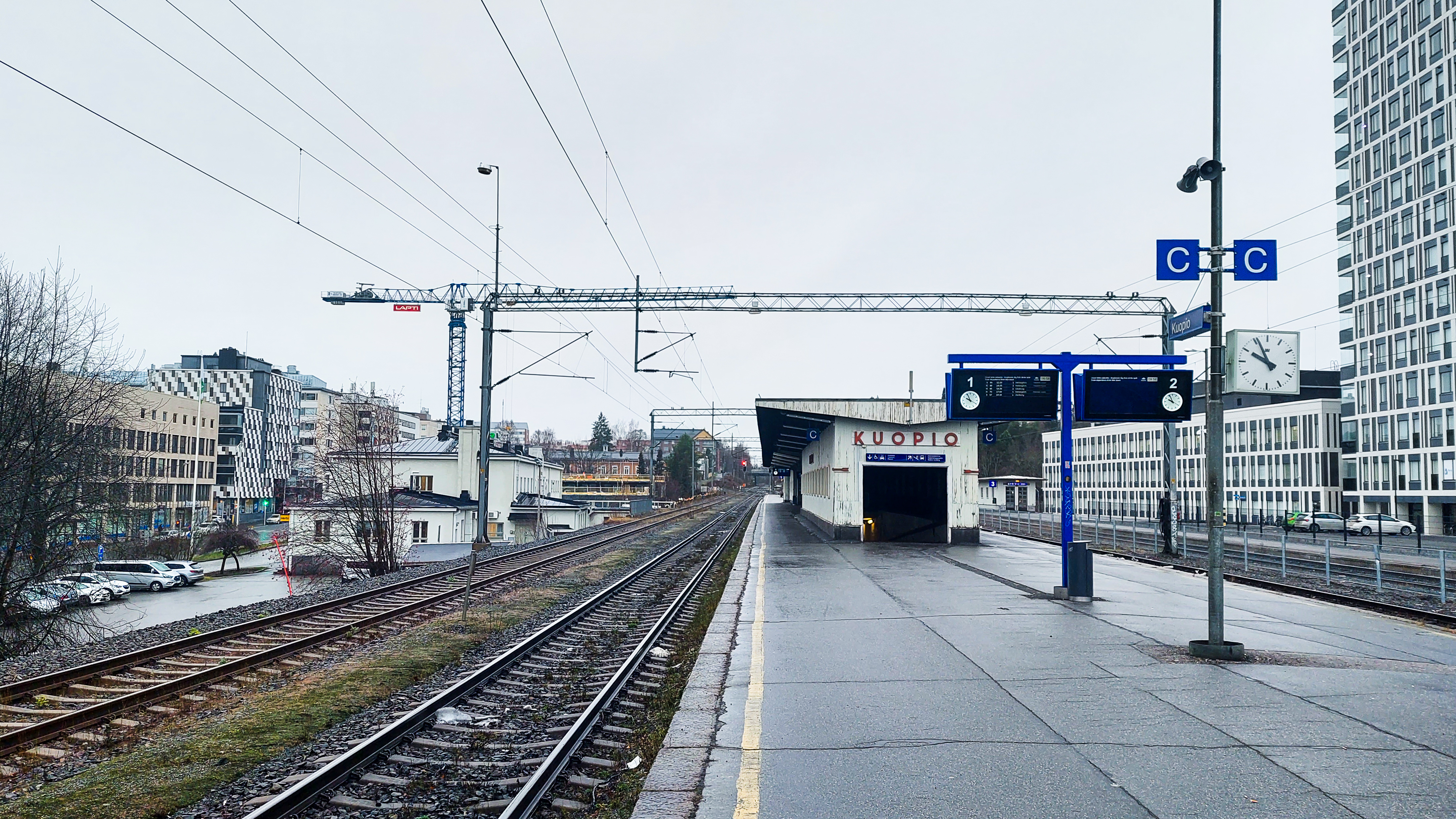 Kuopion ratapiha -hankkeen kuvituskuva, jossa on näkymä Kuopion juna-aseman katoksesta ja kyltistä, jossa lukee Kuopio