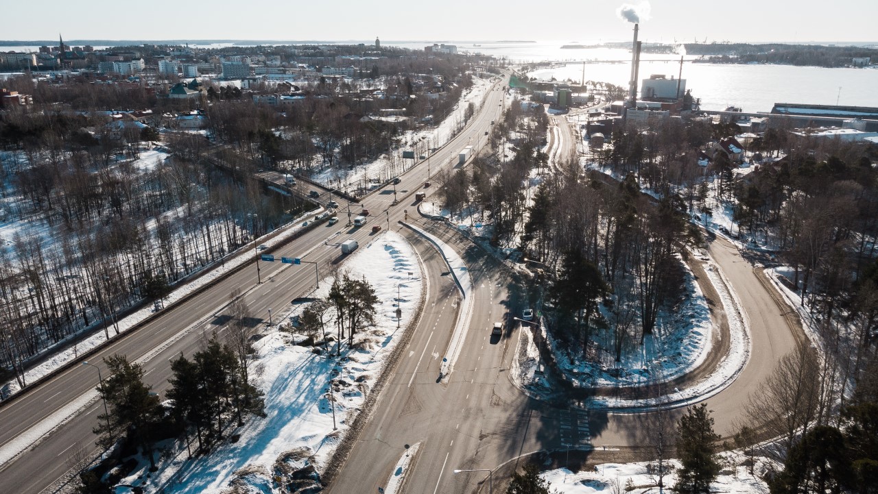 Kuva otettu taivaalta alaspäin ja kuvassa näkyy laajalti Paimenportin risteysalue. On talvi ja aurinko paistaa. Autoja on menossa sataman suuntaan ja tulossa sieltä poispäin. Osa autoista odottaa vuoroaan liikennevaloissa.