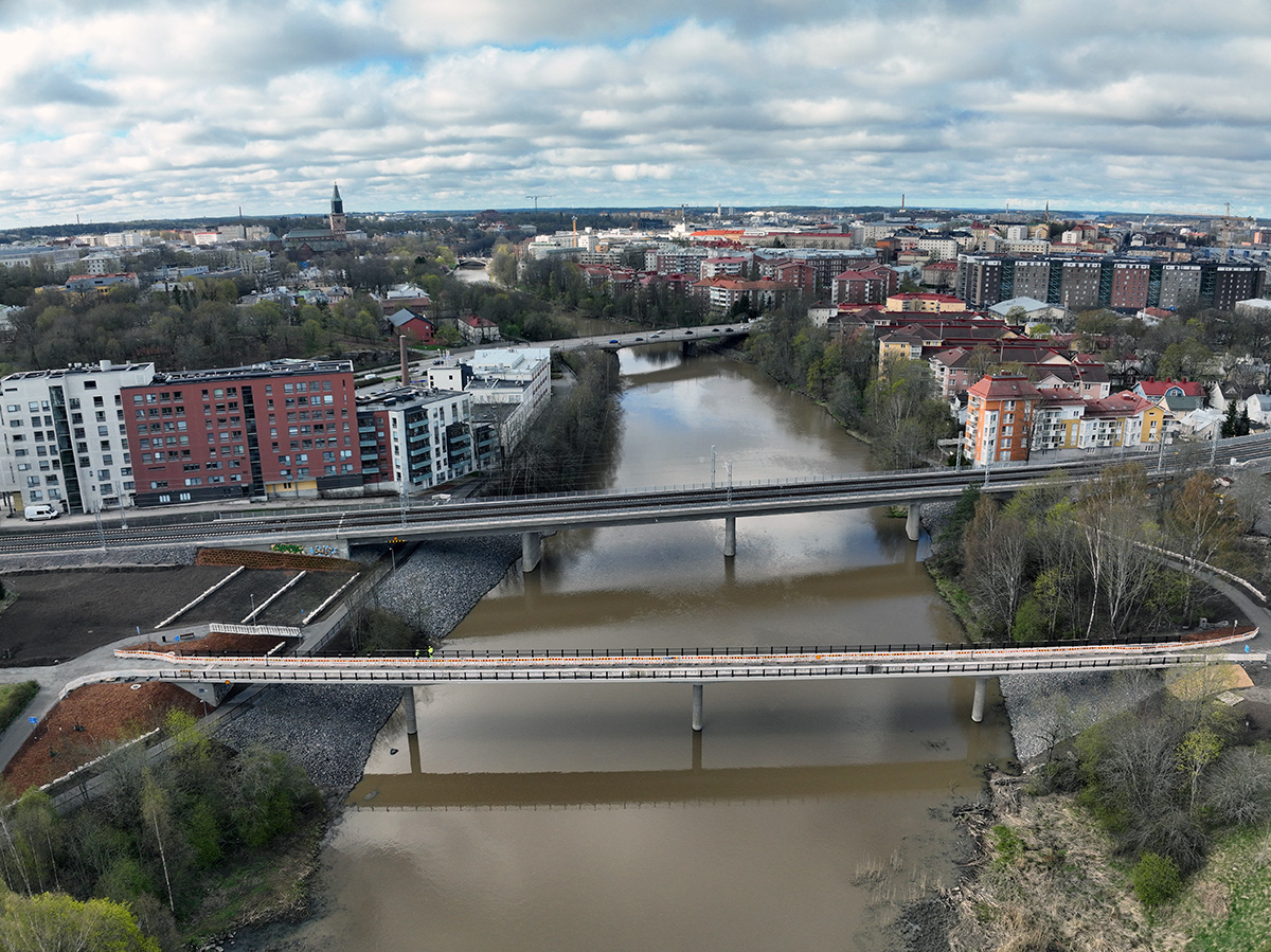 Ilmakuva kaupungista, jossa kaksi siltaa ylittää joen. Taustalla näkyy tiiviisti rakennettu asuinalue sekä kirkon torni horisontissa. Joen rannat ovat vehreitä, ja sää on puolipilvinen.