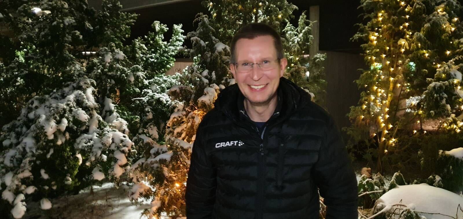 Kupittaa-Turku-ratahankkeen projektipäällikkö Erkki Mäkelä seisoo jouluvaloilla koristeltujen, lumisten kuusten edessä.