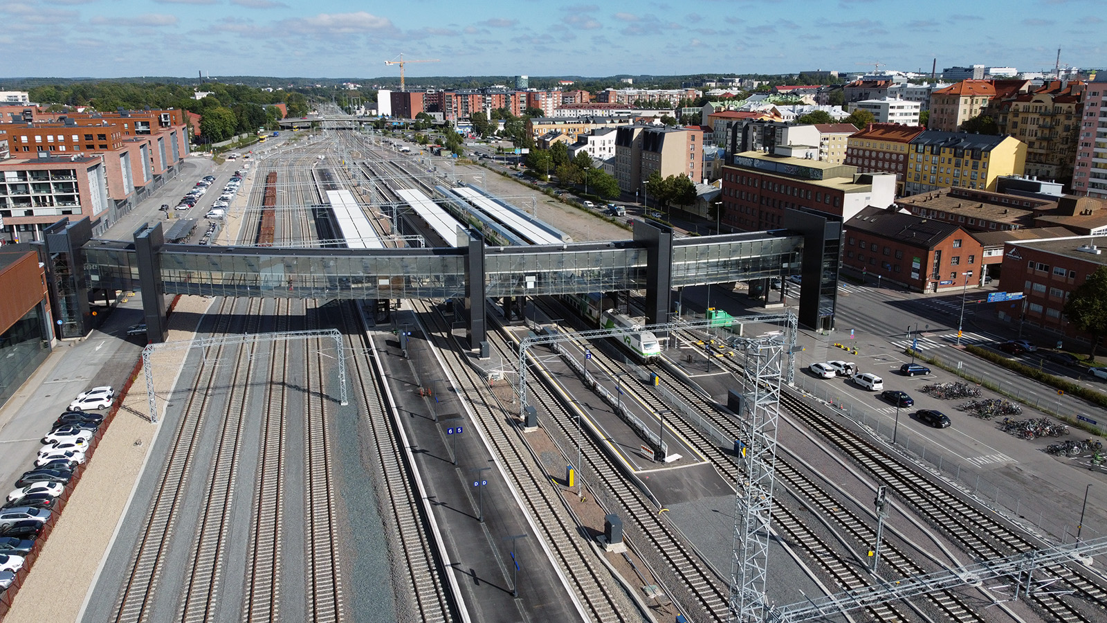 Ilmakuva rautatieasemasta, jossa on useita raiteita, junia ja kävelysilta rakennusten ympäröimänä.