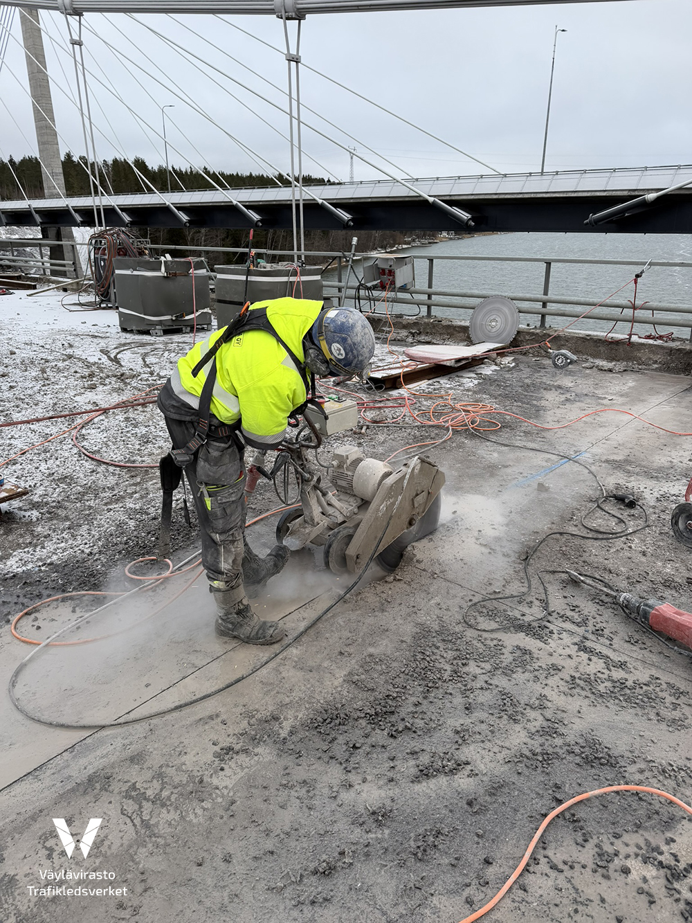 mies työvaatteissa sahaa betonia