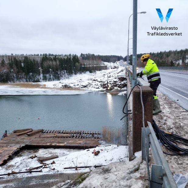 Snöigt landskap från Hessundsbron. Byggnadsarbetaren drar ledningar mellan brons räcken och ljusstolpen.