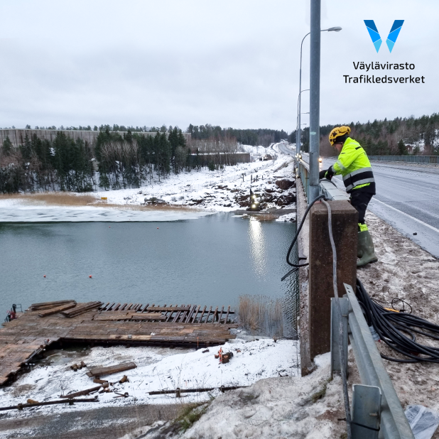 Luminen maisema Hessundinsalmen sillasta. Rakennusmies vetää johtoja sillan kaiteiden ja valopylvään välistä.