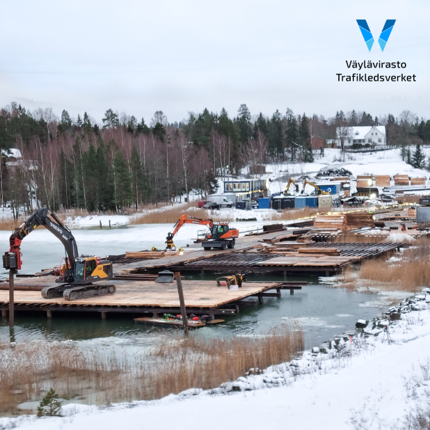 Rakenteilla oleva työsilta, jonka päällä työkoneita ja rakennusmateriaaleja.