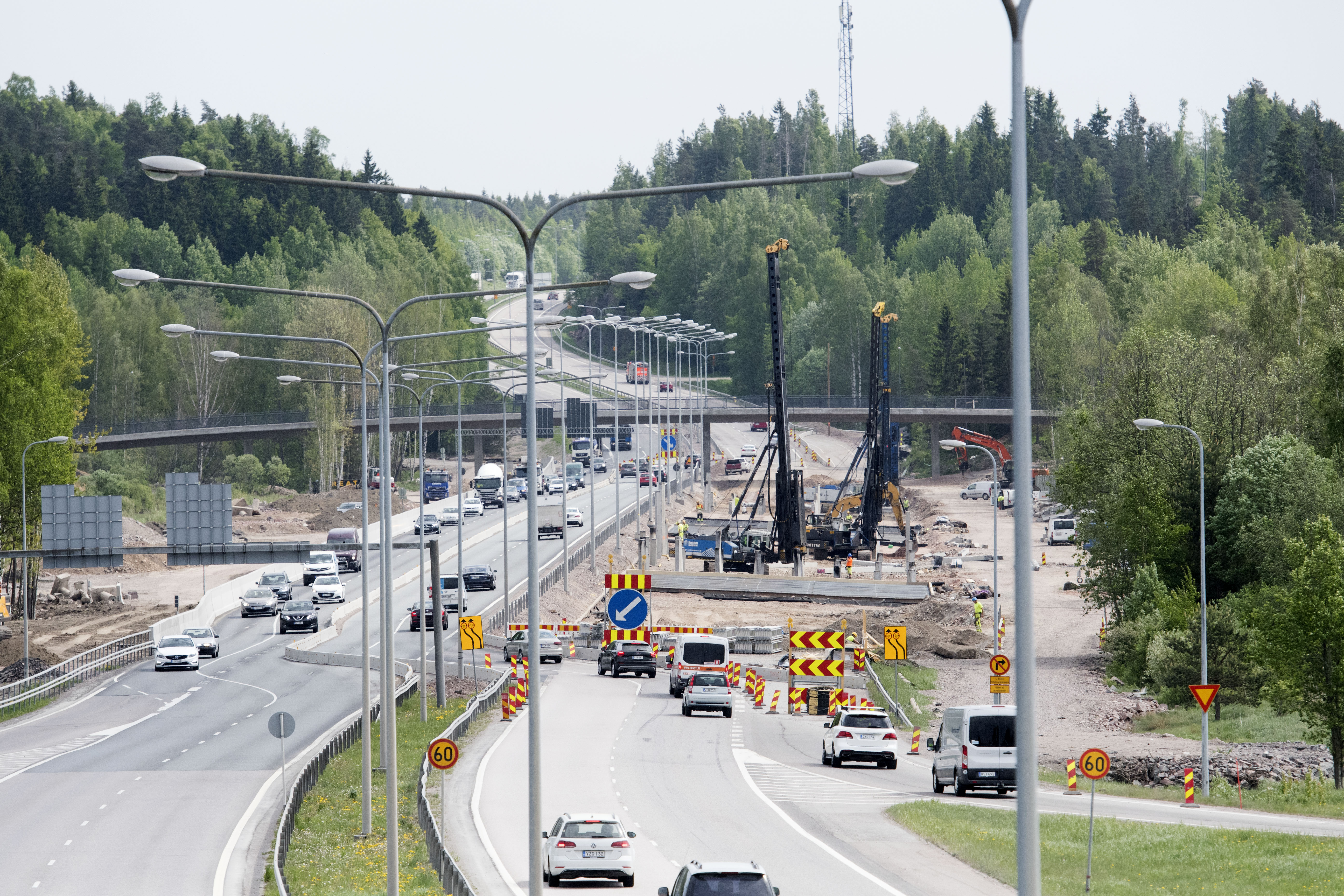 A summery road construction site with traffic passing by.