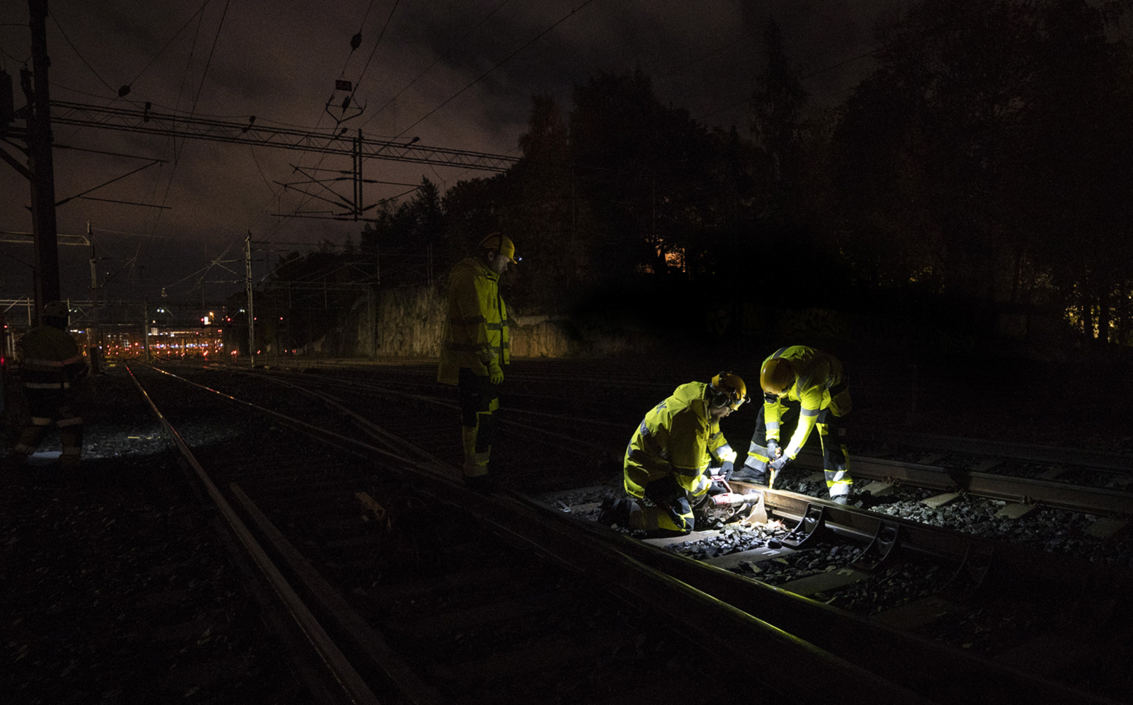 At night, workmen are renovating a railway line near the Helsinki Railway Station.