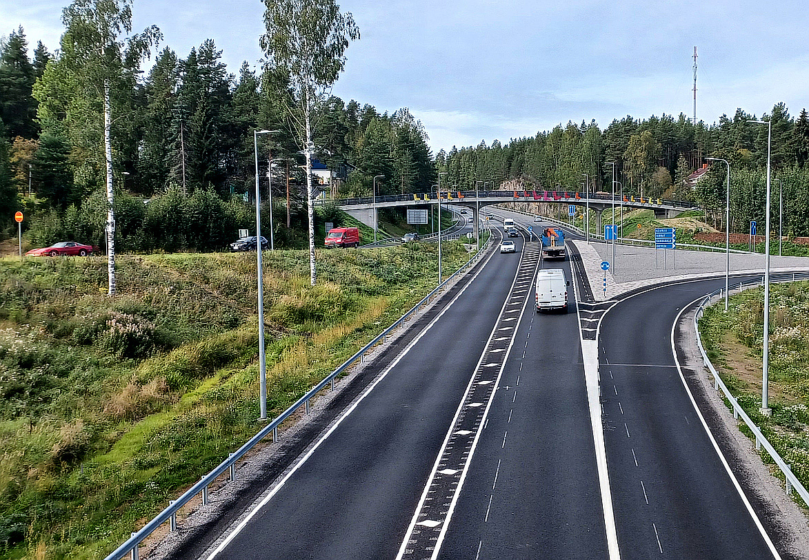 Kumpaankin suuntaan vilkasta liikennettä. Uutta mustaa asfalttia ja taustalla uusittu kevyen liikenteen silta.